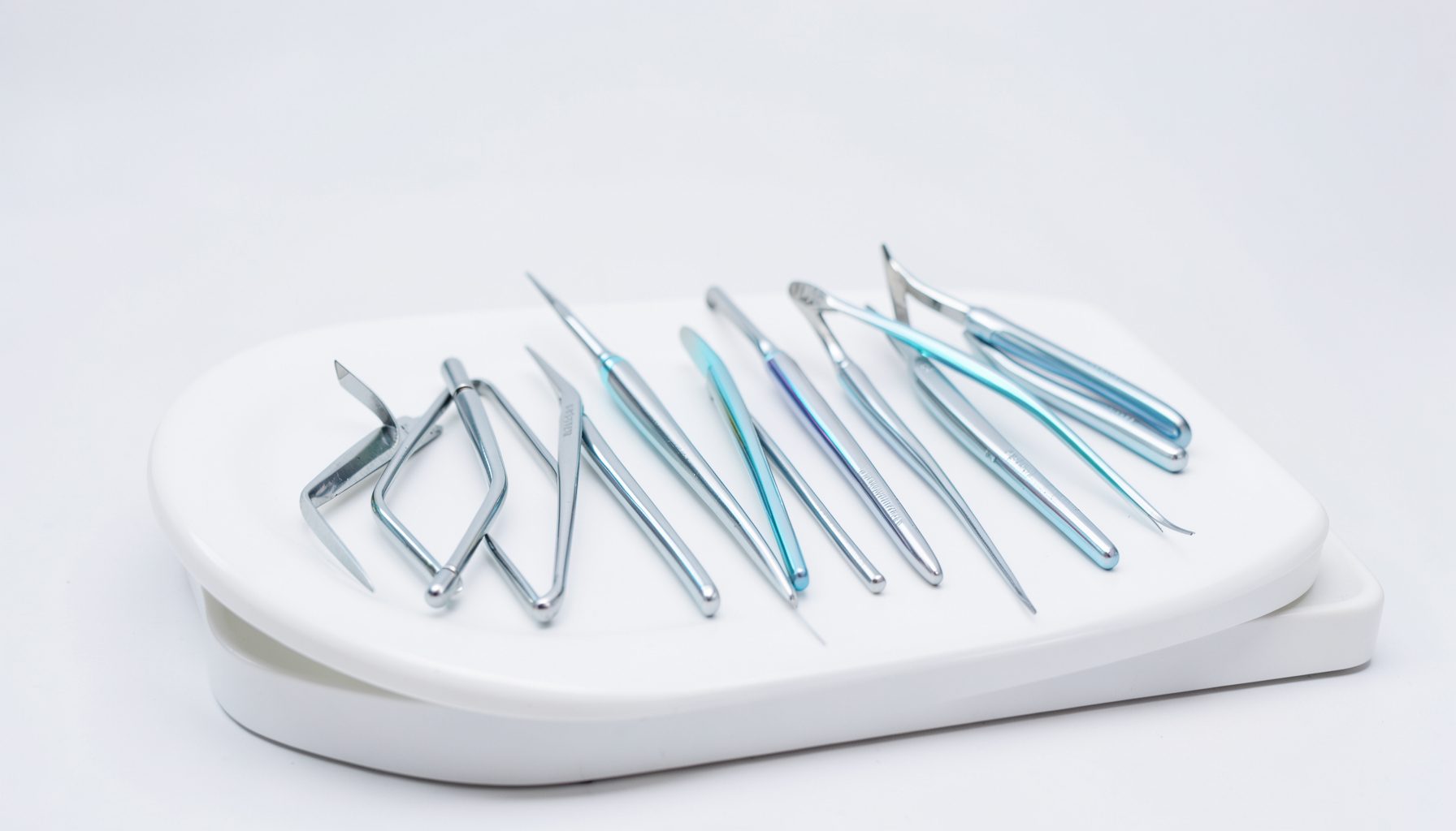 Primo piano di strumenti odontoiatrici disposti ordinatamente su un vassoio bianco, con riflessi argentati e blu tenui