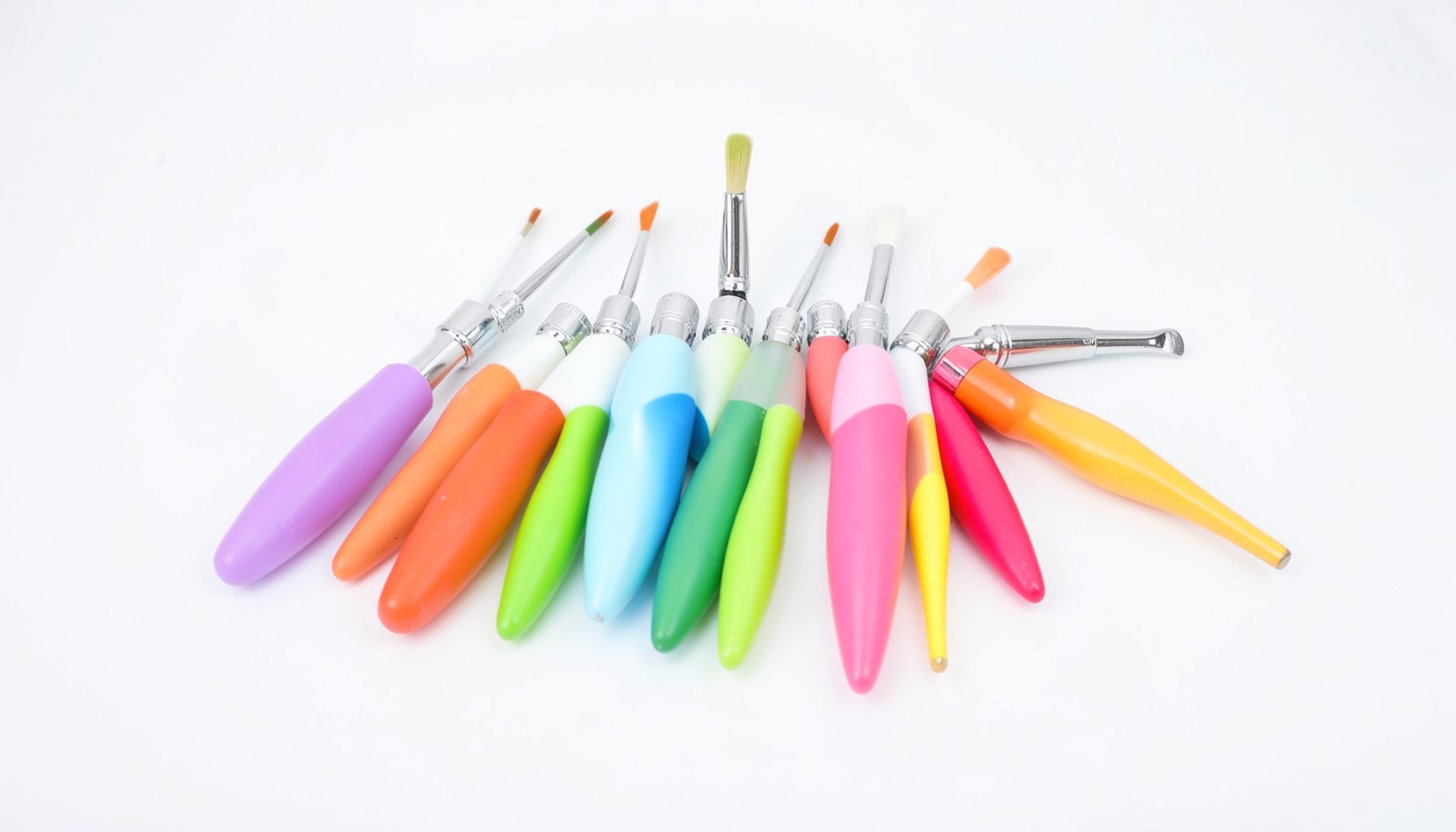 Set di pennelli odontoiatrici con manici colorati su superficie bianca da studio